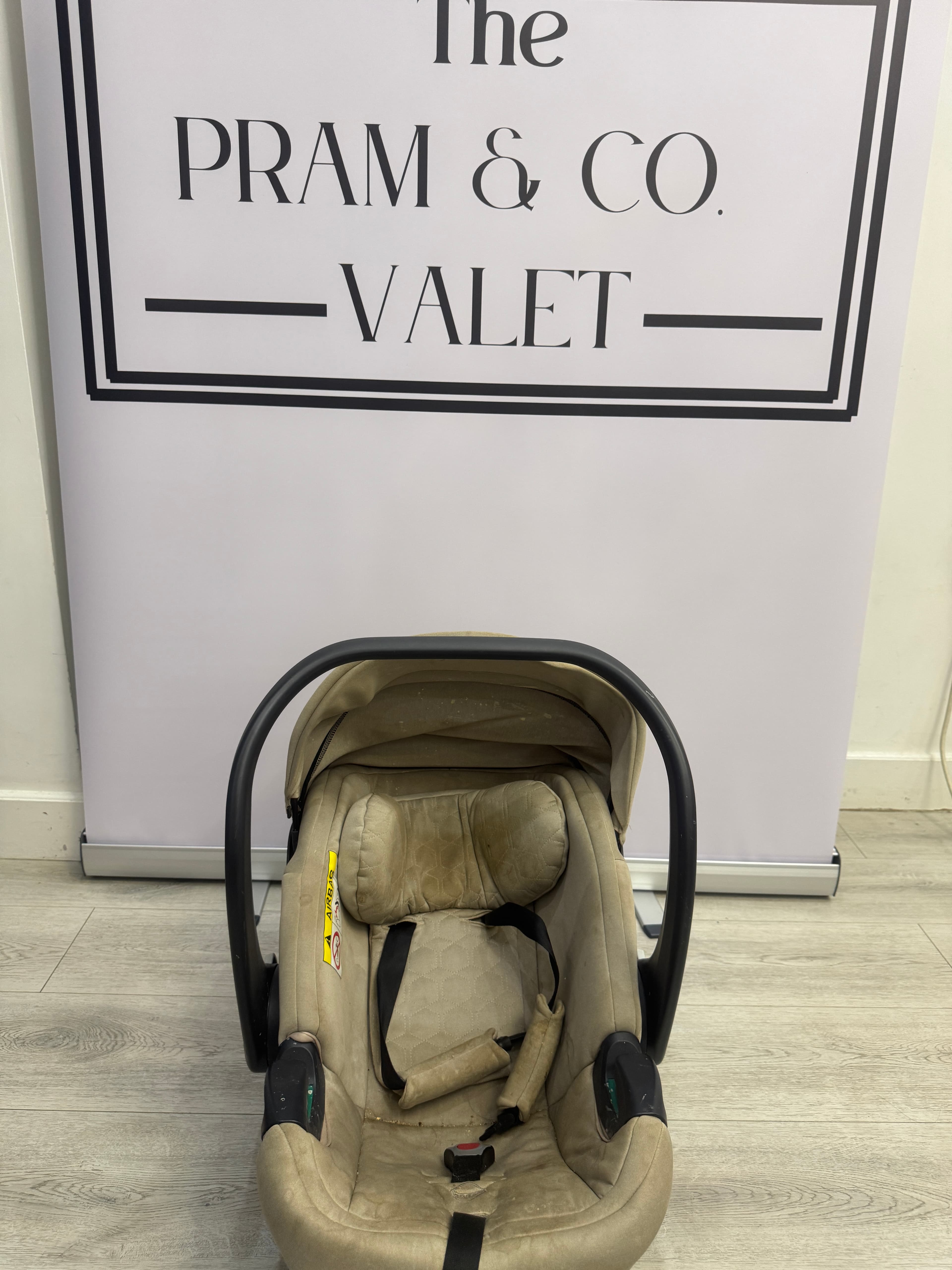 Before cleaning, an Egg car seat with marked fabric and harness area.